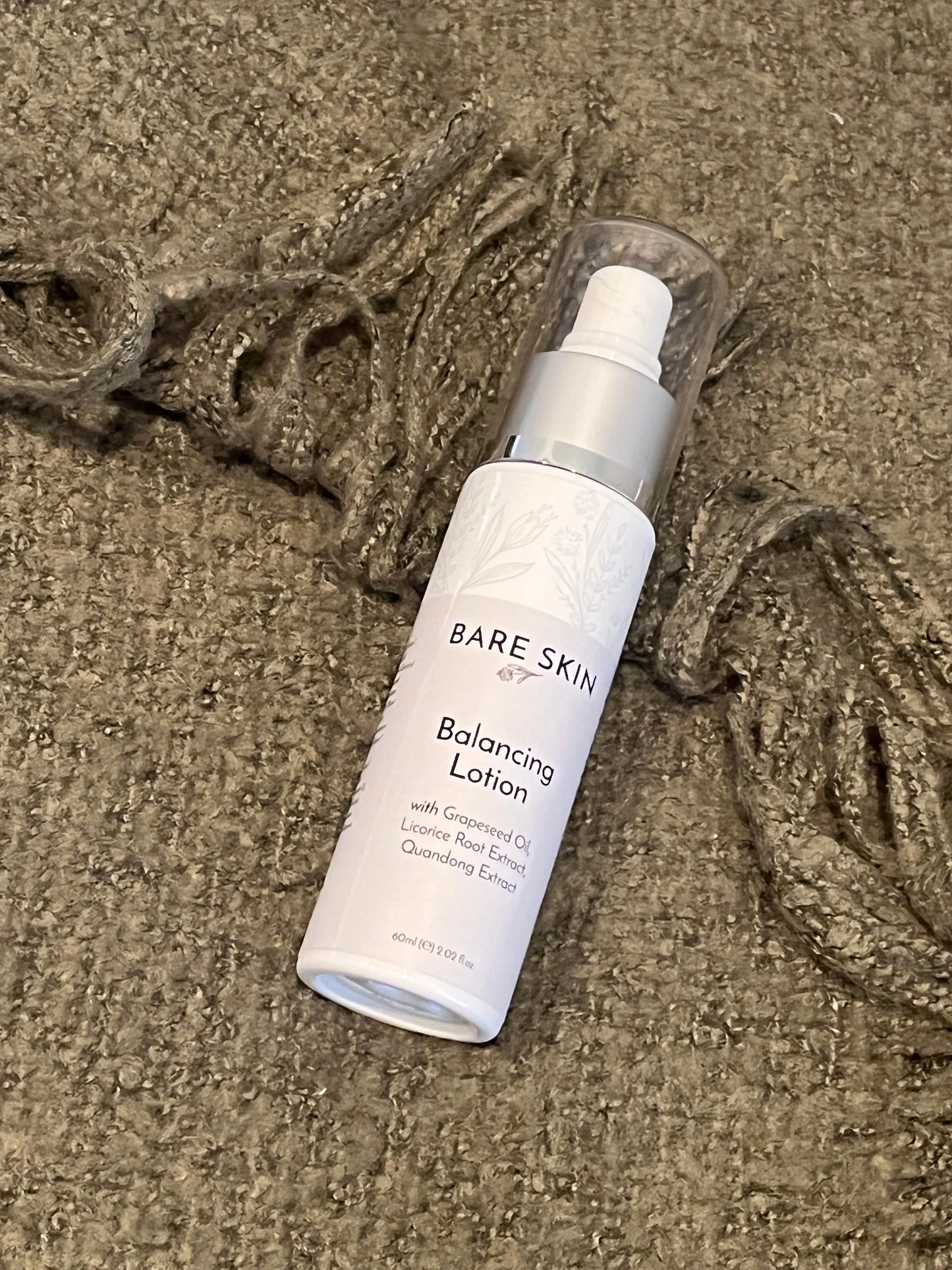 Bare Skin Balancing Lotion lightweight matte moisturiser bottle on green blanket, daily skincare for oily and acne-prone skin.