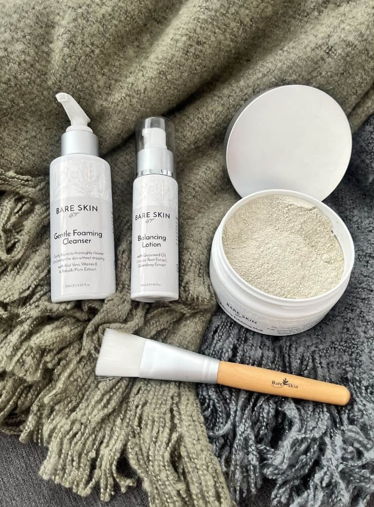 Bare Skin Clear Skin Starter Kit with Gentle Foaming Cleanser, Balancing Enzyme Mask, Balancing Lotion and mask brush on grey blanket, 3 step acne routine to purify detoxify and hydrate skin.