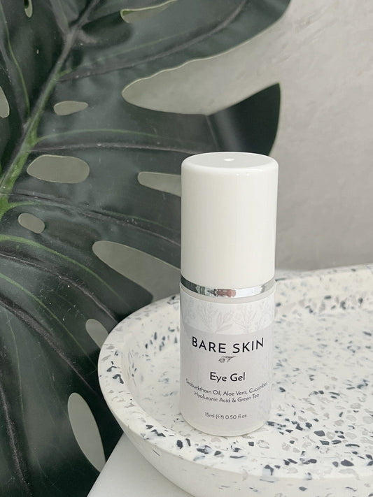 Bare Skin Cooling Eye Gel with Aloe Vera, Cucumber and Green Tea bottle on speckled ceramic tray with leafy background, soothing hydrating eye care.