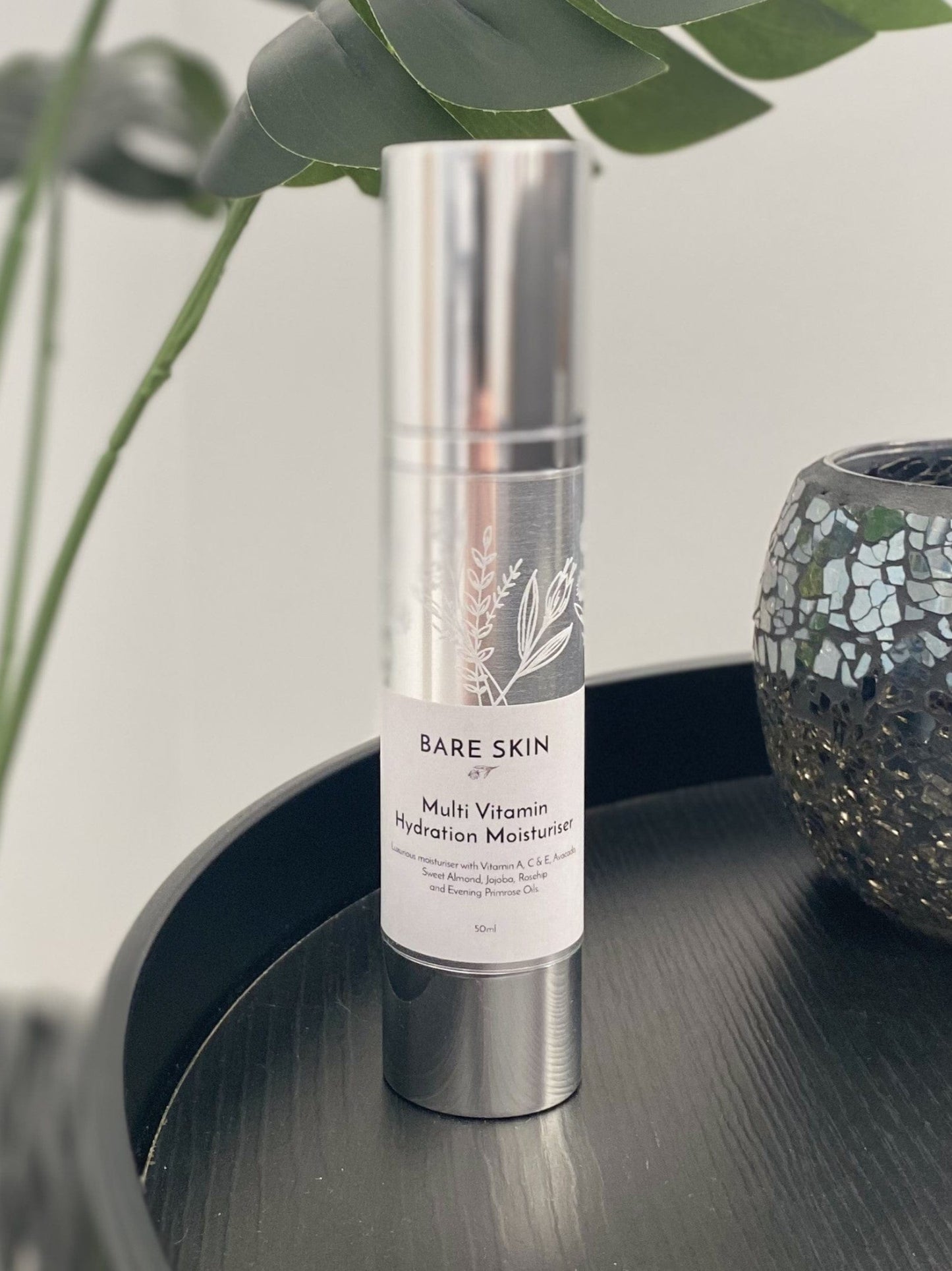 Bare Skin Multi Vitamin Moisturiser sitting on a table with a plant in the background
