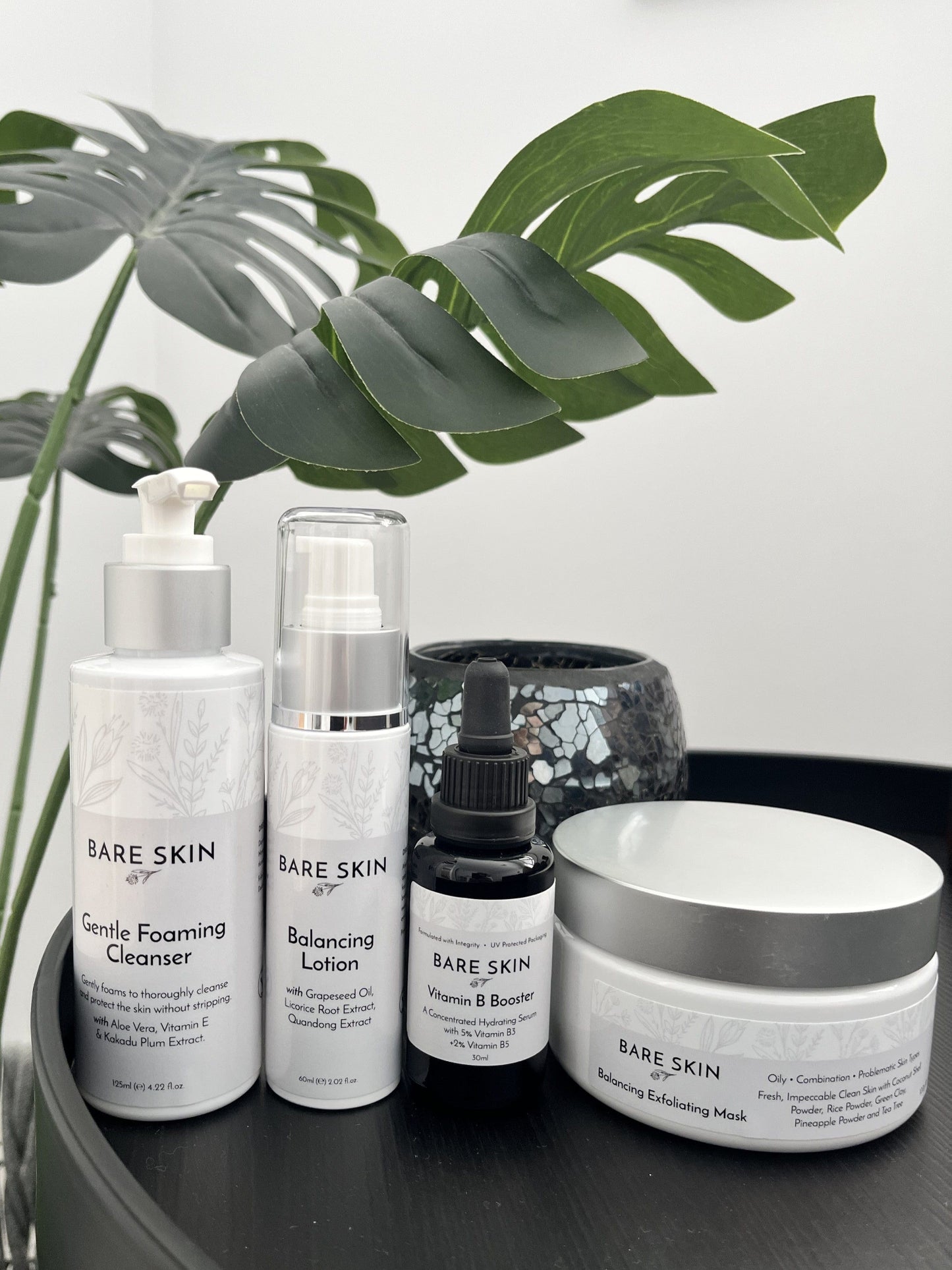 Bare Skin Teen Clear Skin Kit products on a dark surface with plant in background, skincare for acne, blemishes and healthy skin.