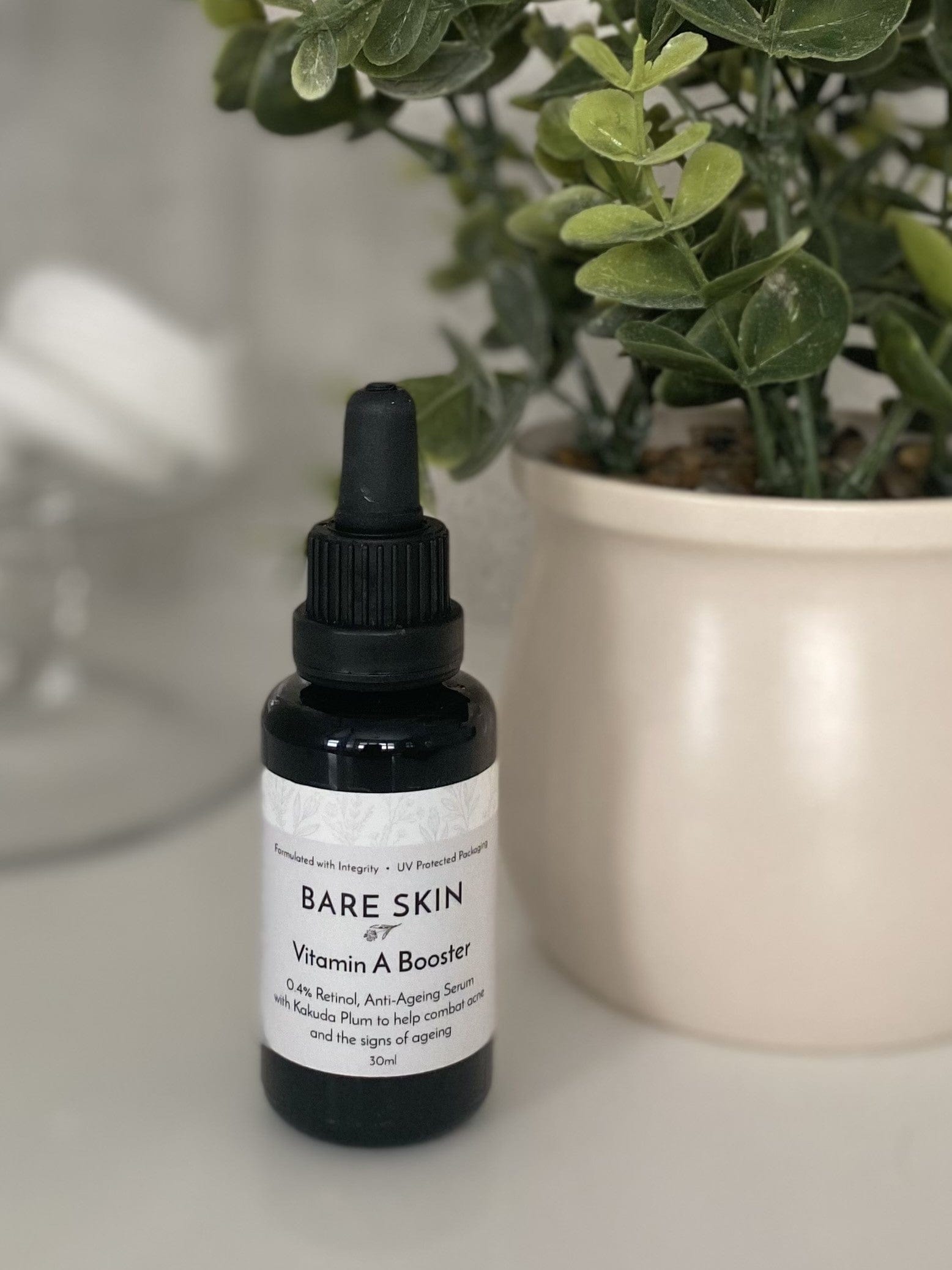 Bare Skin Vitamin A Booster encapsulated retinol serum for sensitive skin bottle on surface with plant in background, barrier-friendly anti-aging serum.