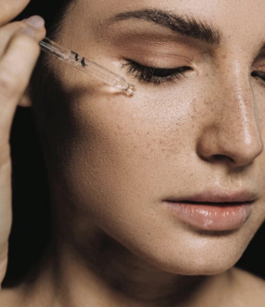 Woman applying Bare Skin serum to the face.