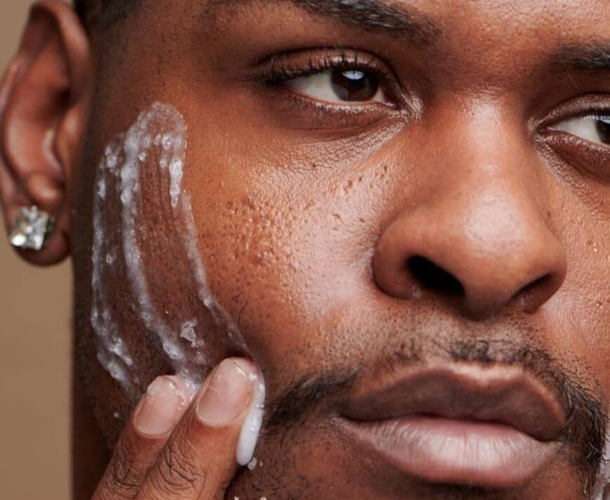 Man applying Bare Skin Balancing Lotion lightweight matte moisturiser against neutral background, skincare for oily and acne-prone skin.
