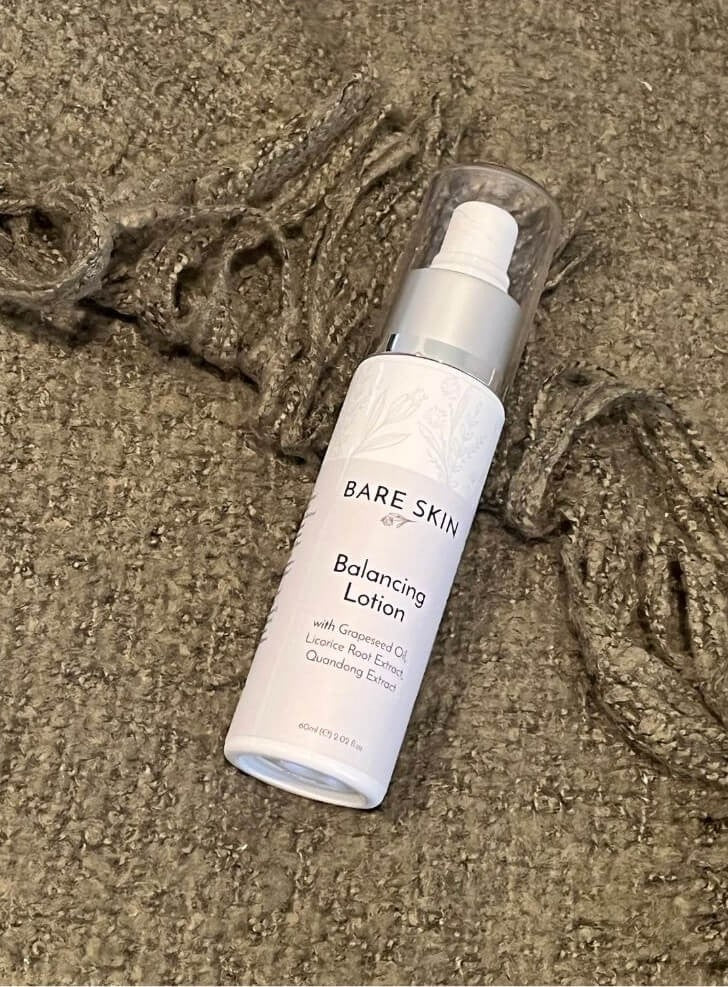 Bare Skin Balancing Lotion lightweight matte moisturiser bottle on green blanket, daily skincare for oily and acne-prone skin.