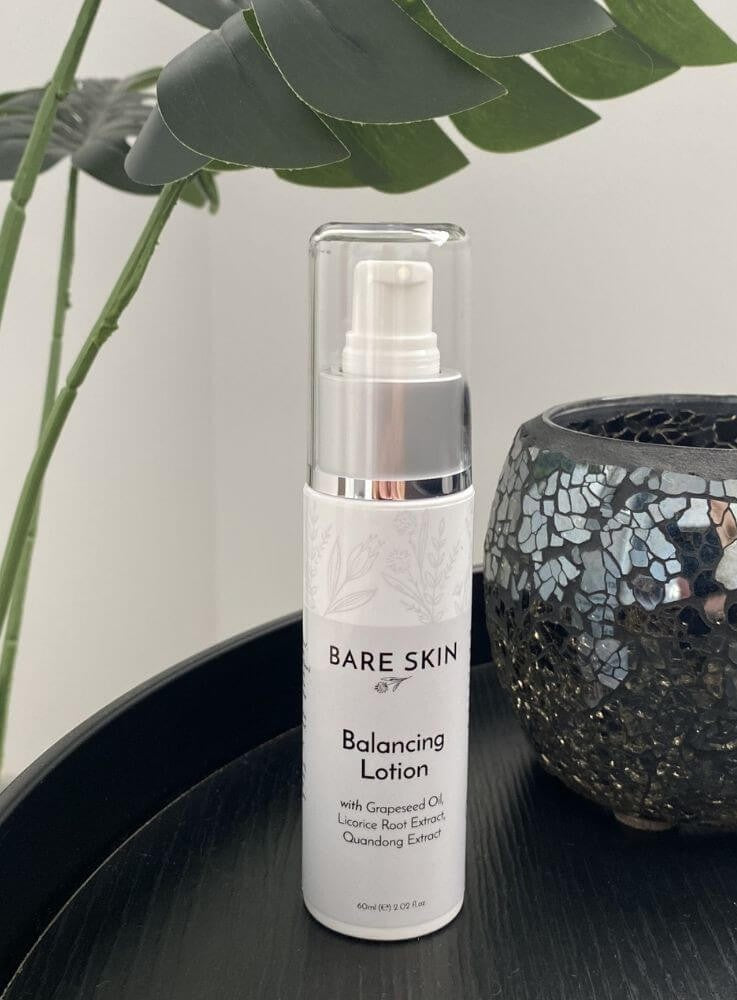 Bare Skin Balancing Lotion lightweight matte moisturiser on dark black table with plant and mosaic vase in background, skincare for acne and oily skin.