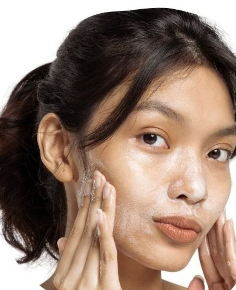 Woman applying Bare Skin Gentle Foaming Cleanser to her face on a white background