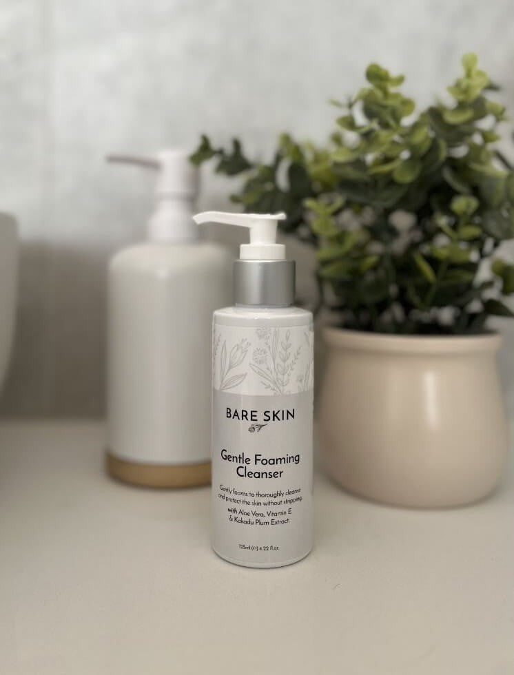 Bare Skin Gentle Foaming Cleanser bottle on a surface with a plant in the background