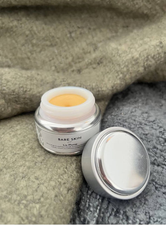Bare Skin Lip Plump open container laying on a green blanket