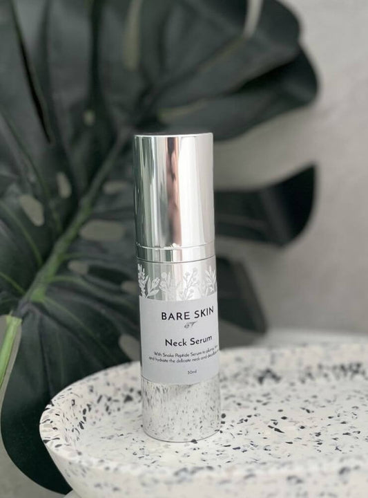 Bare Skin Neck Serum bottle on a speckled surface with a plant in the background