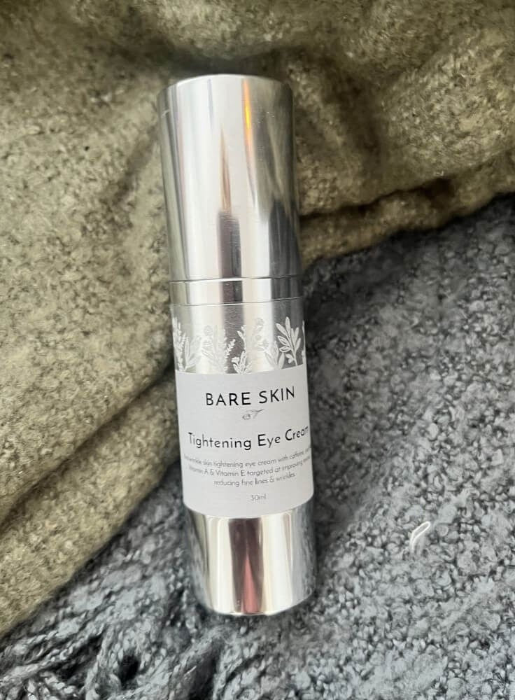 Bottle of Bare Skin Tightening Eye Cream laying on a green and grey blanket