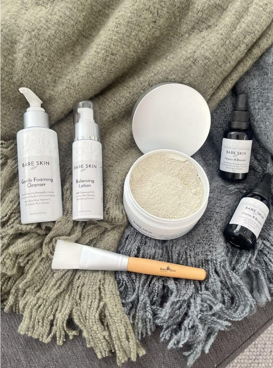 Bare Skin Ultra Clear Skin Kit with Gentle Foaming Cleanser, Vitamin B Booster, Vitamin A Booster, Balancing Enzyme Mask, Balancing Lotion and mask brush on green and grey blankets, intensive 5 step acne routine for clearer healthier skin.