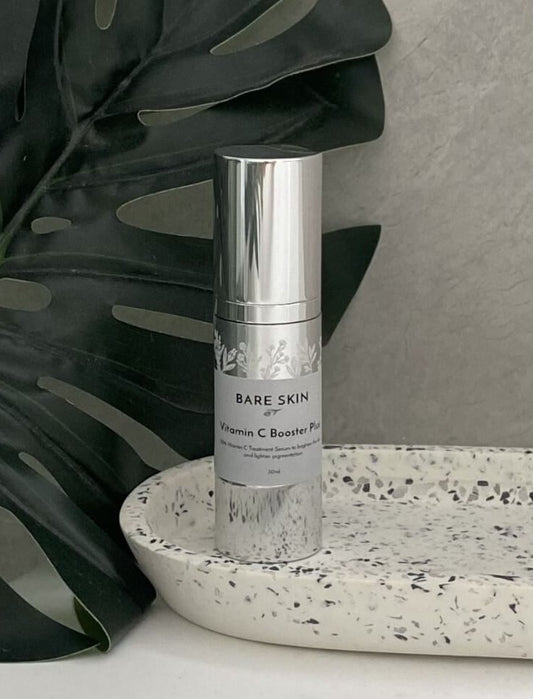 Bare Skin Vitamin C Booster Plus sitting on a textured surface with leaves in the background